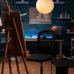 A decorative photo of an artist's studio with an easel and chair.