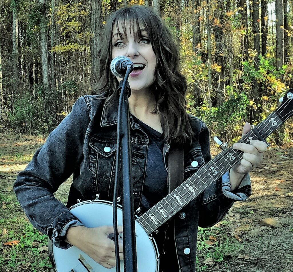 A photo of Stephanie Belinda Quinn singing and playing banjo.